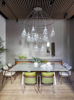 Chandelier with clustered hanging elements positioned above a dining table, providing layered lighting and visual interest
