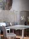 Dining chairs arranged around a rectangular table in a refined interior, showing their clean lines and supportive high backrests within a contemporary dining space
