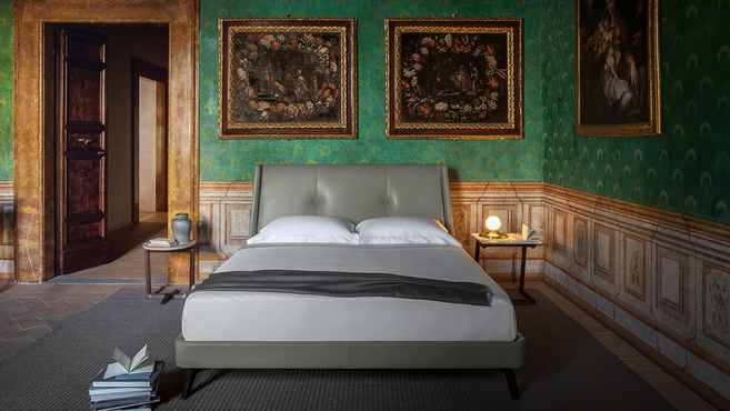 Suzie Wong bed by Poltrona Frau styled in an elegant bedroom interior with bedside tables and decorative wall art, highlighting the upholstered bed within a refined residential setting