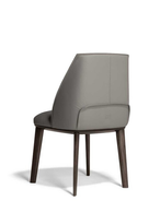 Archibald dining chair by Poltrona Frau shown from the rear highlighting the curved backrest, tailored upholstery and wooden leg detail.