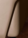 Close-up of the Coupé bed headboard edge showing the smooth curved form and tailored upholstery