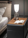 Lamp placed on a bedside table next to a bed, offering functional lighting for reading and a warm, intimate atmosphere