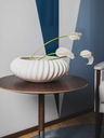Shiwa vase by Poltrona Frau shown with flowers on a table highlighting its low sculptural form and decorative interior use.