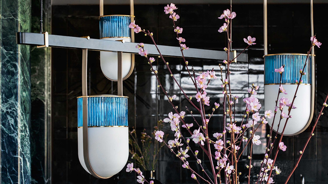 Xi Suspension pendant lamp by Poltrona Frau styled in a refined interior with decorative branches and architectural backdrop, highlighting the suspended lighting design