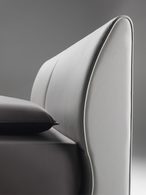 Angled view of the Eosonno bed headboard and frame highlighting the curved profile and refined stitching