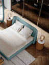 Table lamp placed beside a bed on a round side table, providing soft lighting and complementing the bedroom arrangement