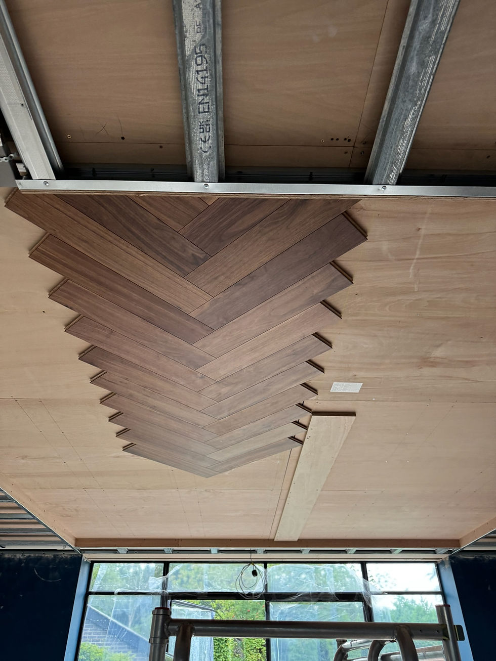 Close-up of the walnut herringbone pattern being installed on the feature ceiling.