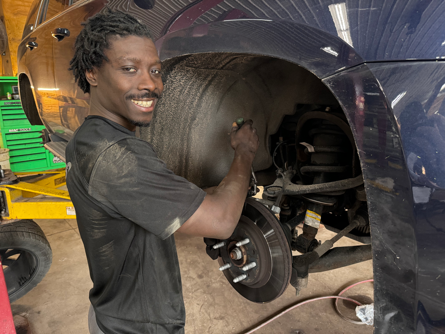 Smiling mechanic working on car's wheel well