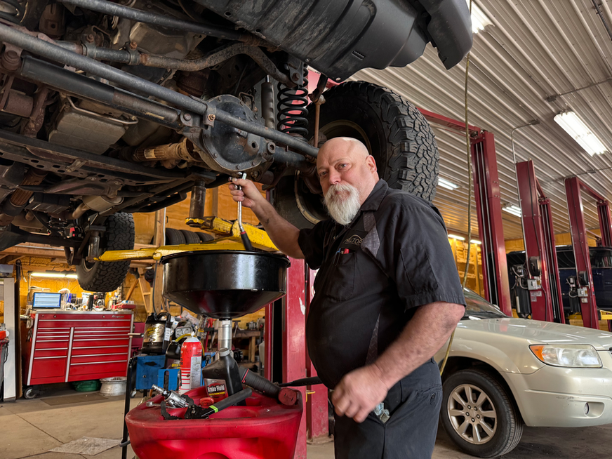 Mechanic with wrench under lifted car in auto shop