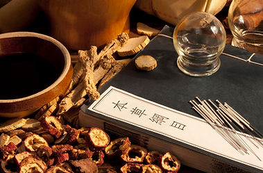 Table decorated with Chinese herbs, acupuncture needles and a Chinese medicine textbook