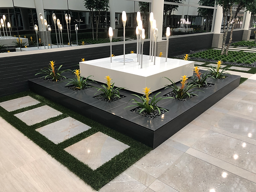 Commercial courtyard with modern tile, stone trough, planter, and bromeliads in a high-end office building