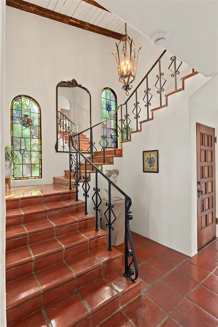 Central stair with terracotta treads, iron railing, and stained glass at 1239 Geneva Street
