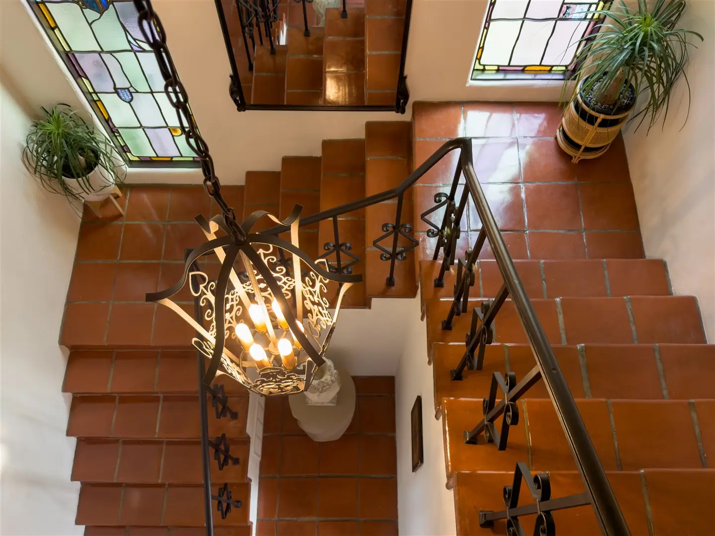 Central stair with terracotta treads, iron railing, and stained glass at 1239 Geneva Street