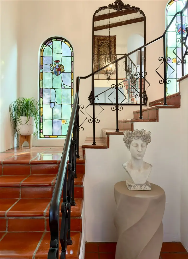 Central stair with terracotta treads, iron railing, and stained glass at 1239 Geneva Street