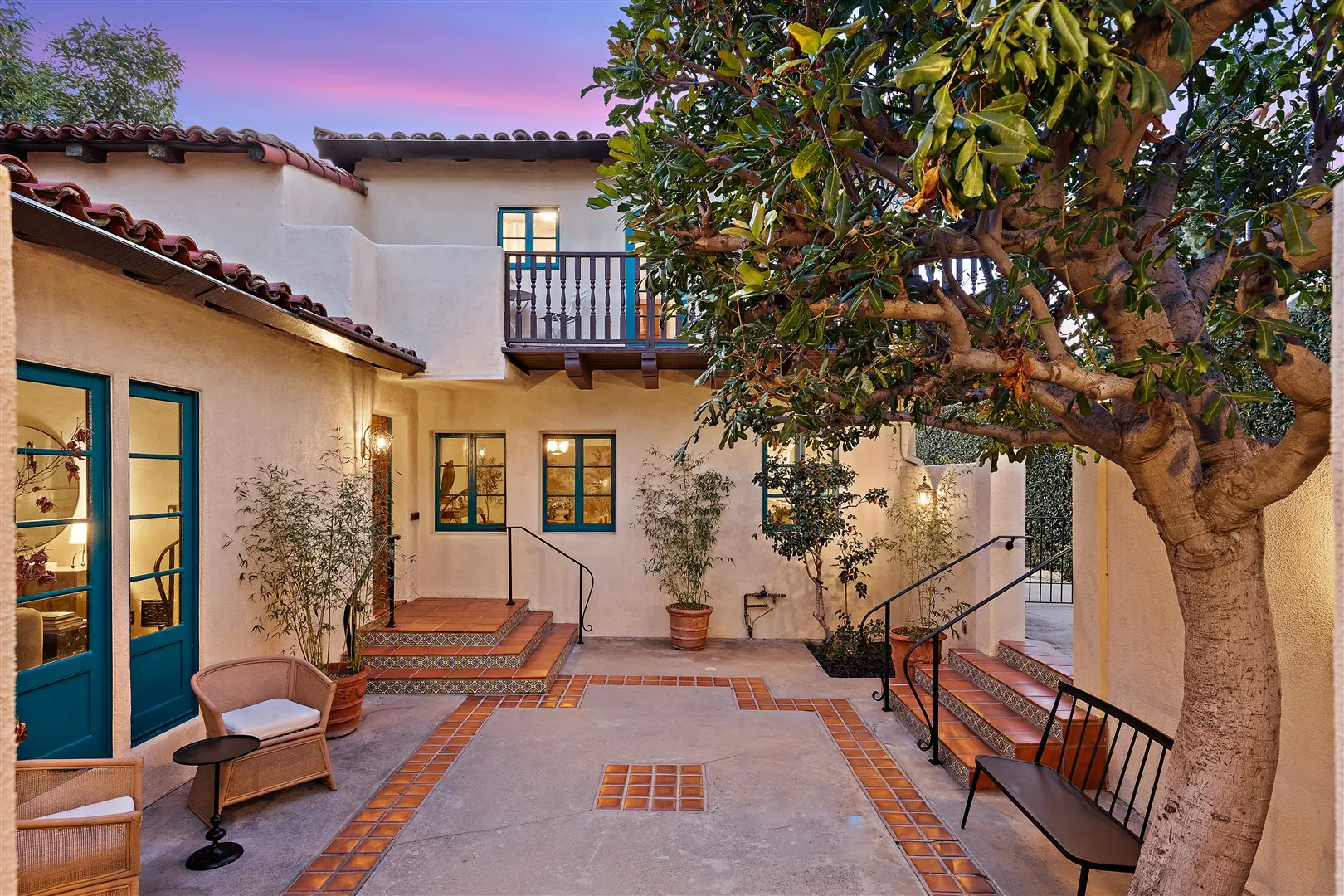 Spanish Revival courtyard with mature tree and plaster walls at 1239 Geneva Street