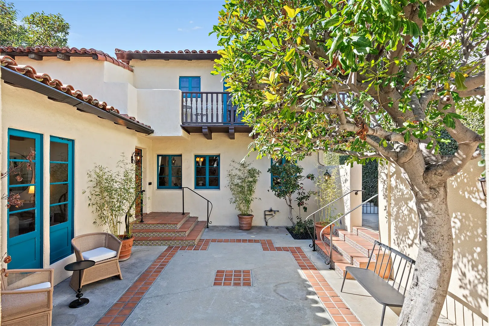 Courtyard tree framed by the two-story Spanish Revival exterior at 1239 Geneva Street