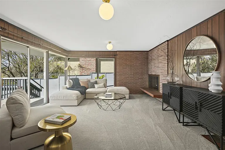Family room at 783 Balra Drive with wood paneling and brick fireplace