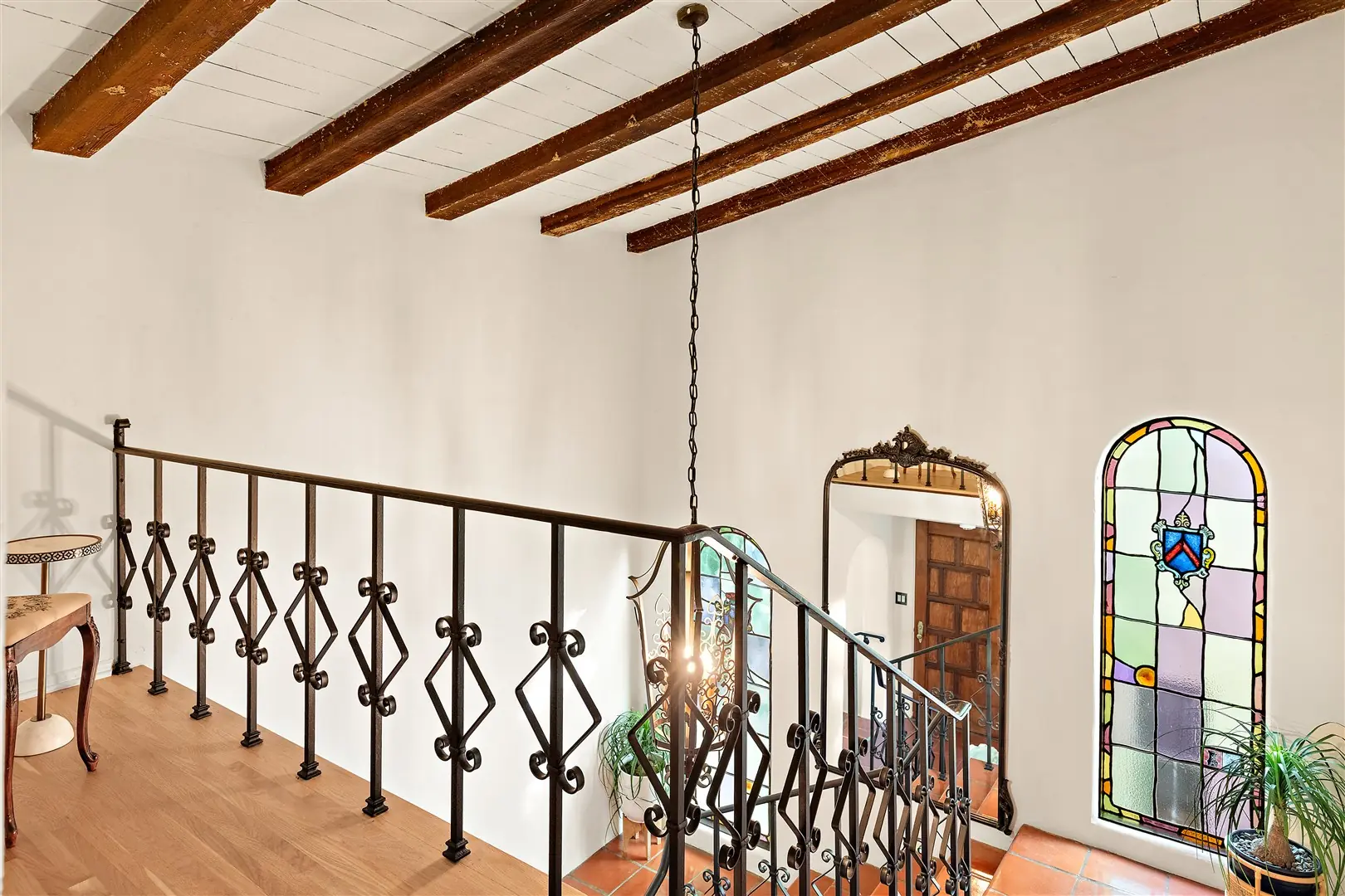 Central stair with terracotta treads, iron railing, and stained glass at 1239 Geneva Street