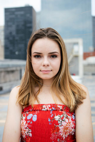 High school senior smiling during an outdoor portrait session in Dallas, Texas