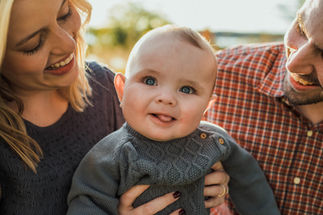 Couple smiling at their baby during an outdoor portrait session at White Rock Lake in Dallas, Texas