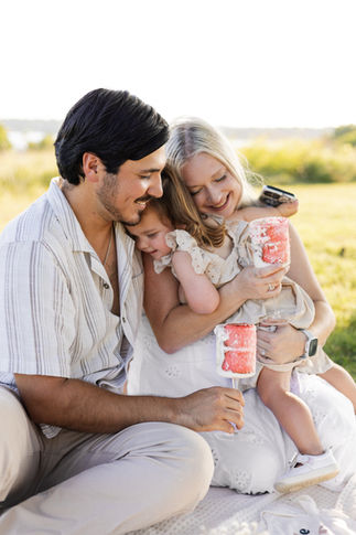 A family hugs during an outdoor gender reveal portrait session in Dallas, Texas