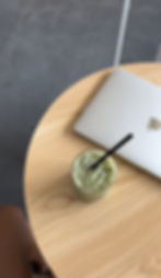 Laptop and cup of iced matcha on a table. 