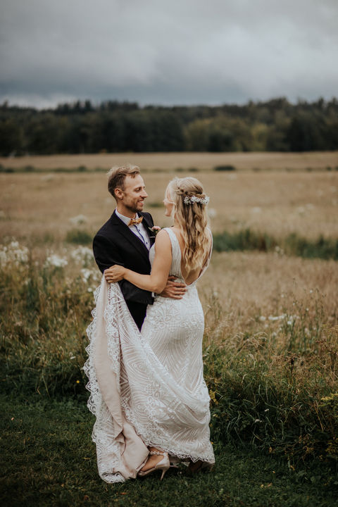 Hääpari seisoo peltoaukealla – luonnonläheinen hääkuvaus Suomessa, dokumentaarinen tyyli