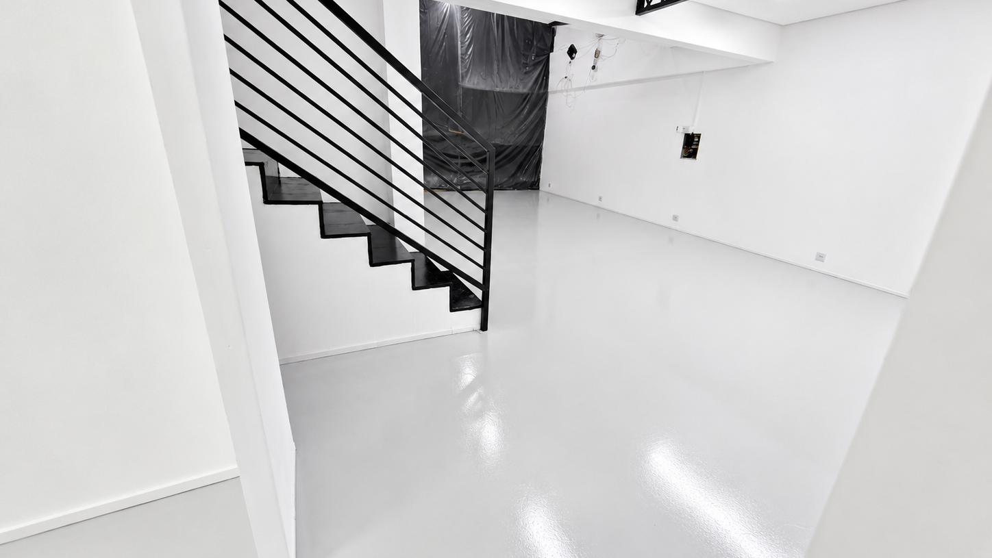 Escada preta em ambiente amplo com piso branco brilhante