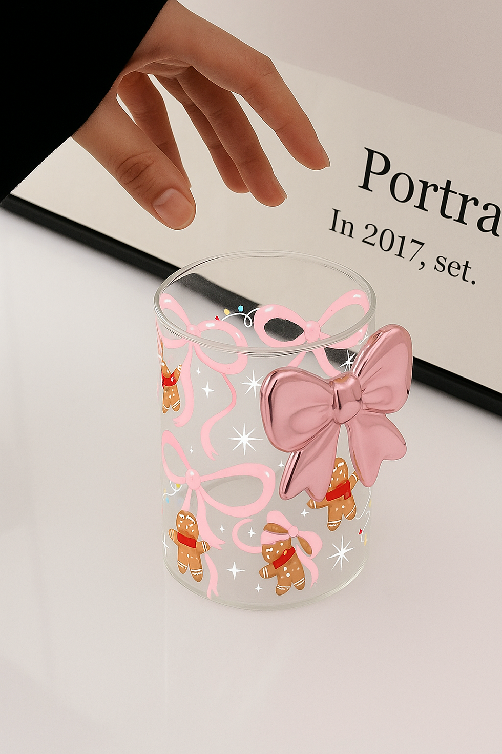 Thumbnail: Hand touching a glass with pink bows and gingerbread figures, Bow Glass.