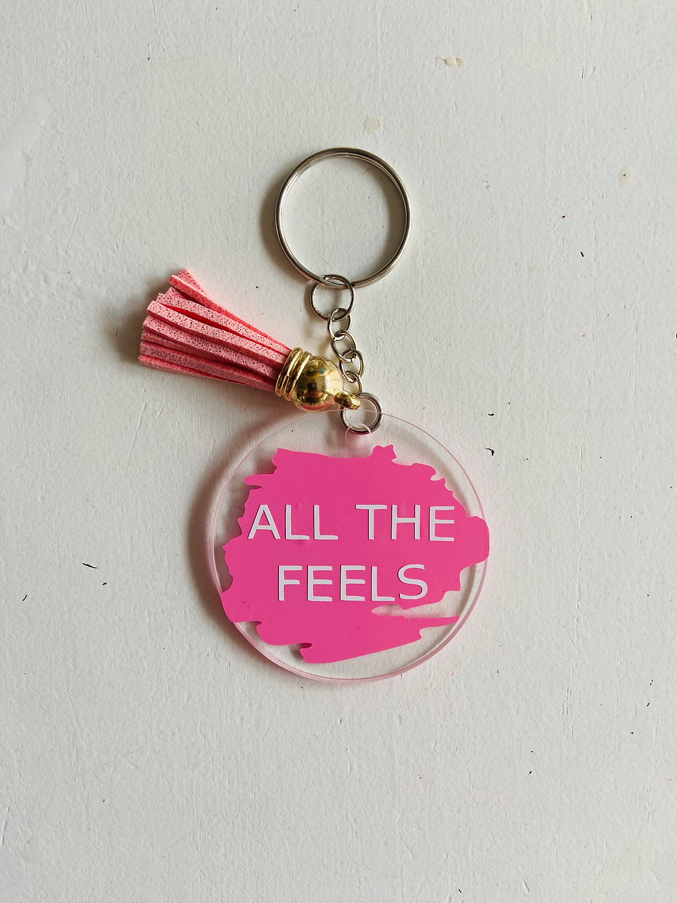 Thumbnail: Pink keychain reading ALL THE FEELS with tassel and silver ring on white surface.