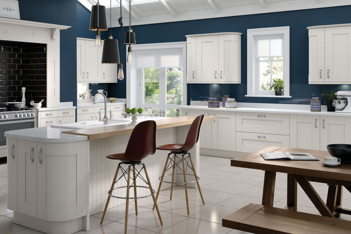 Modern kitchen with white cabinets and navy blue walls, island and stools.