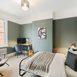 Cole Hill Double Bedroom 2 with green walls, double bed, armchair and desk with computer