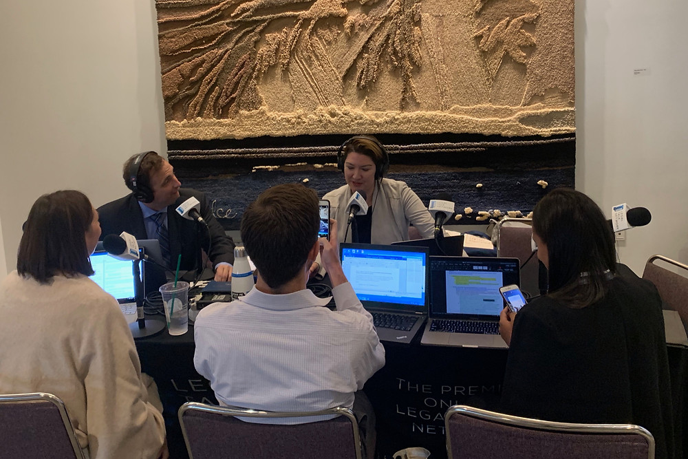 Group of people sitting at a table wearing headphones in front of microphones