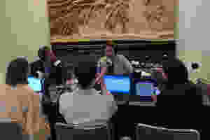 Group of people sitting at a table wearing headphones in front of microphones
