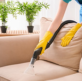 Classic Carpet Cleaning vacuuming couch wearing yellow rubber gloves