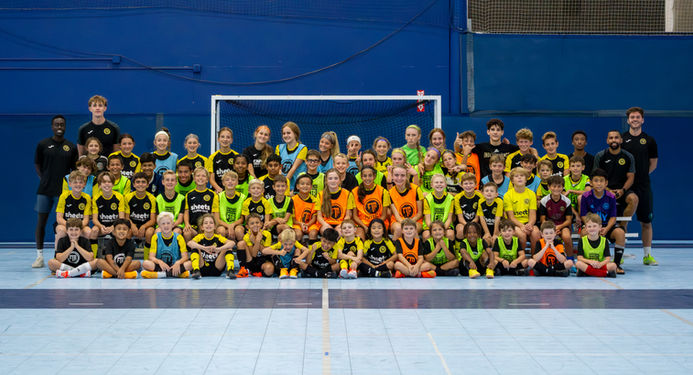 The highest Level of players. Large group of youth futsal players and coaches posing together on an indoor court during a training session