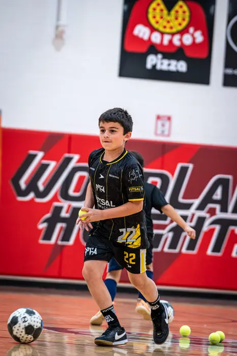 Young boy in black and yellow uniform with a soccer ball