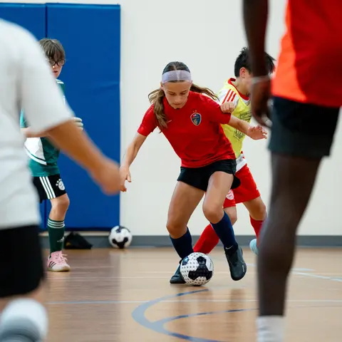 Player in red jersey and headband controlling the ball during small-sided game