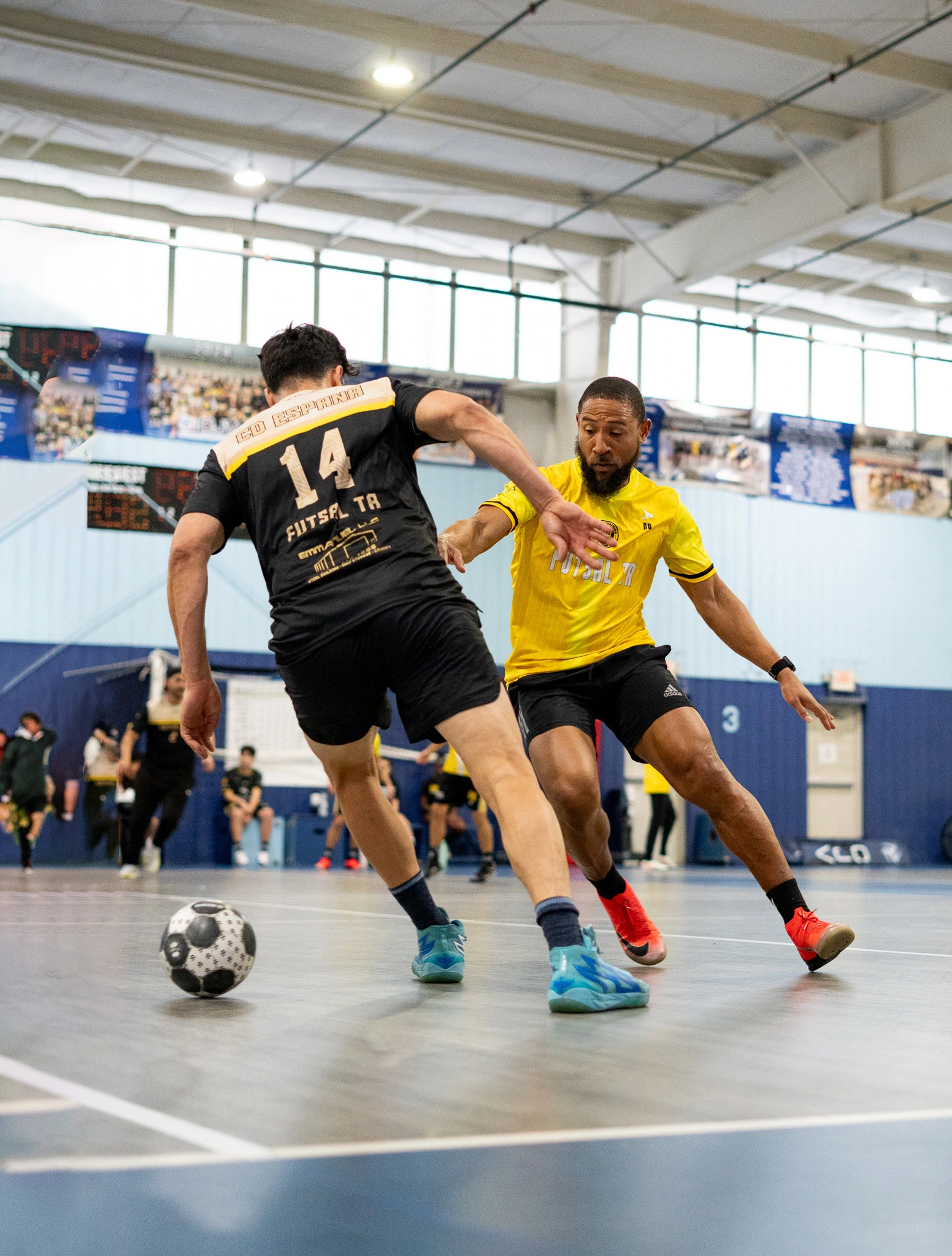 Adult futsal players competing intensely for the ball during high-level indoor futsal match.