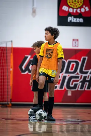 Boy in soccer uniform with ball on indoor court