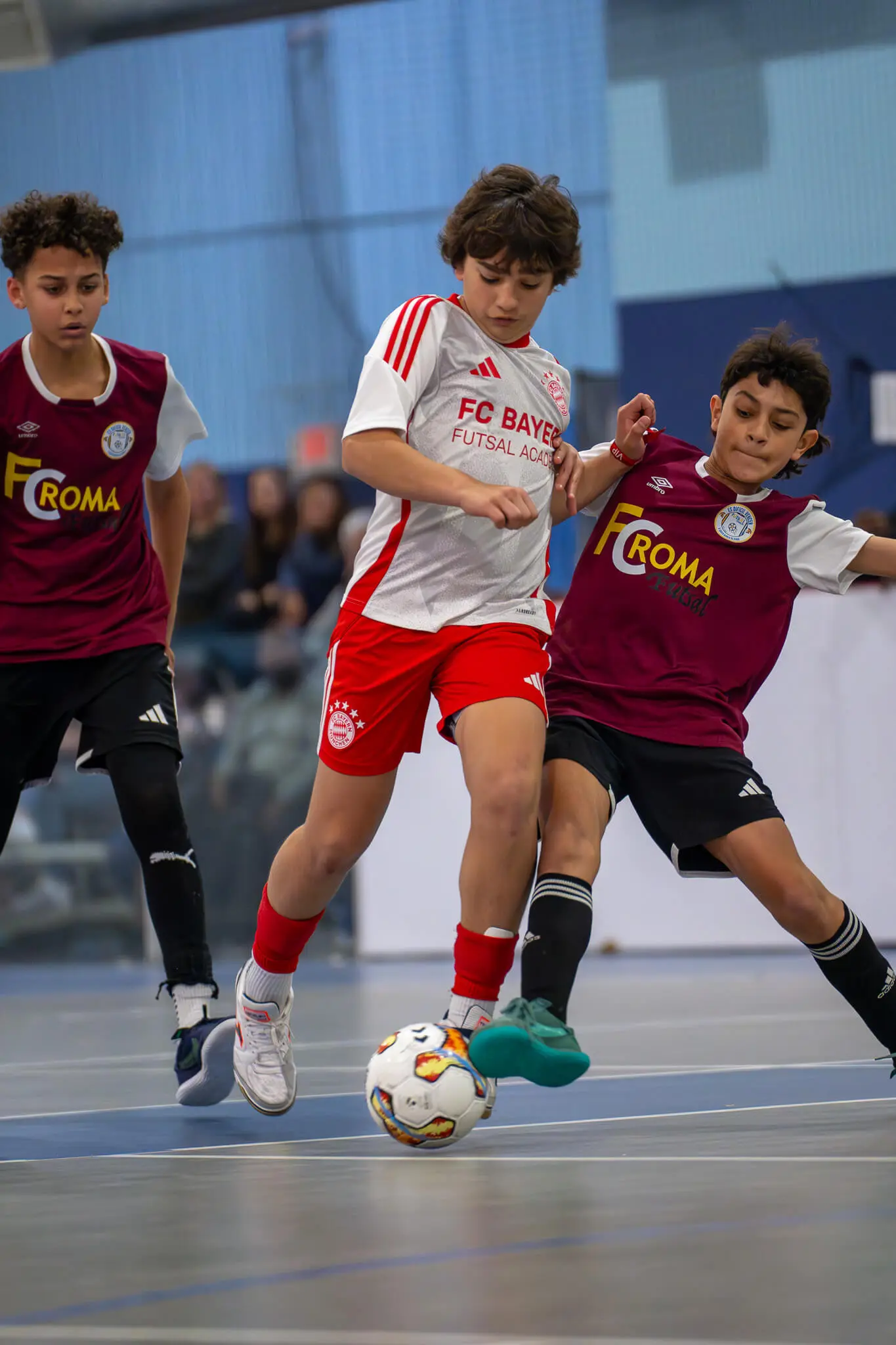 A player dribbling the futsal ball while opposing players fight for the ball