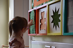 young girl with glasses touching sensory panels on the wall of the playroom