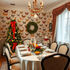 A Christmas dinner table layed out beautifully in front o butterfly wallpaper