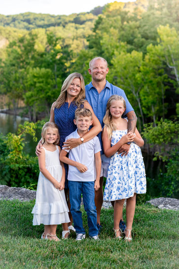 Family posing together with lush green trees and the Ozark hills in the background