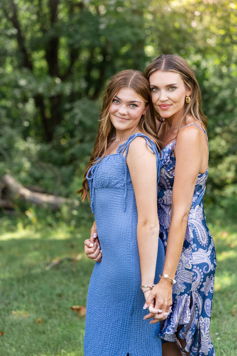 Mom and daughter holding hands outdoors during a family reunion photo session.