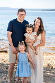 Family posing together beside the blue water of Table Rock Lake with the Ozark hills in the background