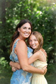 Mother and daughter embracing during extended family photos in Branson among natural greenery.