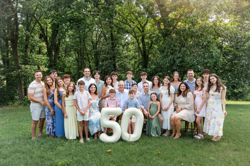 Large extended family portrait captured during a family reunion photography session in Branson. Grand parents hold balloons saying 50 for their anniversary.