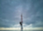 Sailor climbing the mast of a racing yacht at sea under a heavy overcast sky