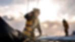 Sailor in yellow offshore gear hauling a line on the deck of an ocean racing yacht at sunset